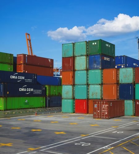 Vibrant shipping containers stacked at an industrial port under a blue sky.